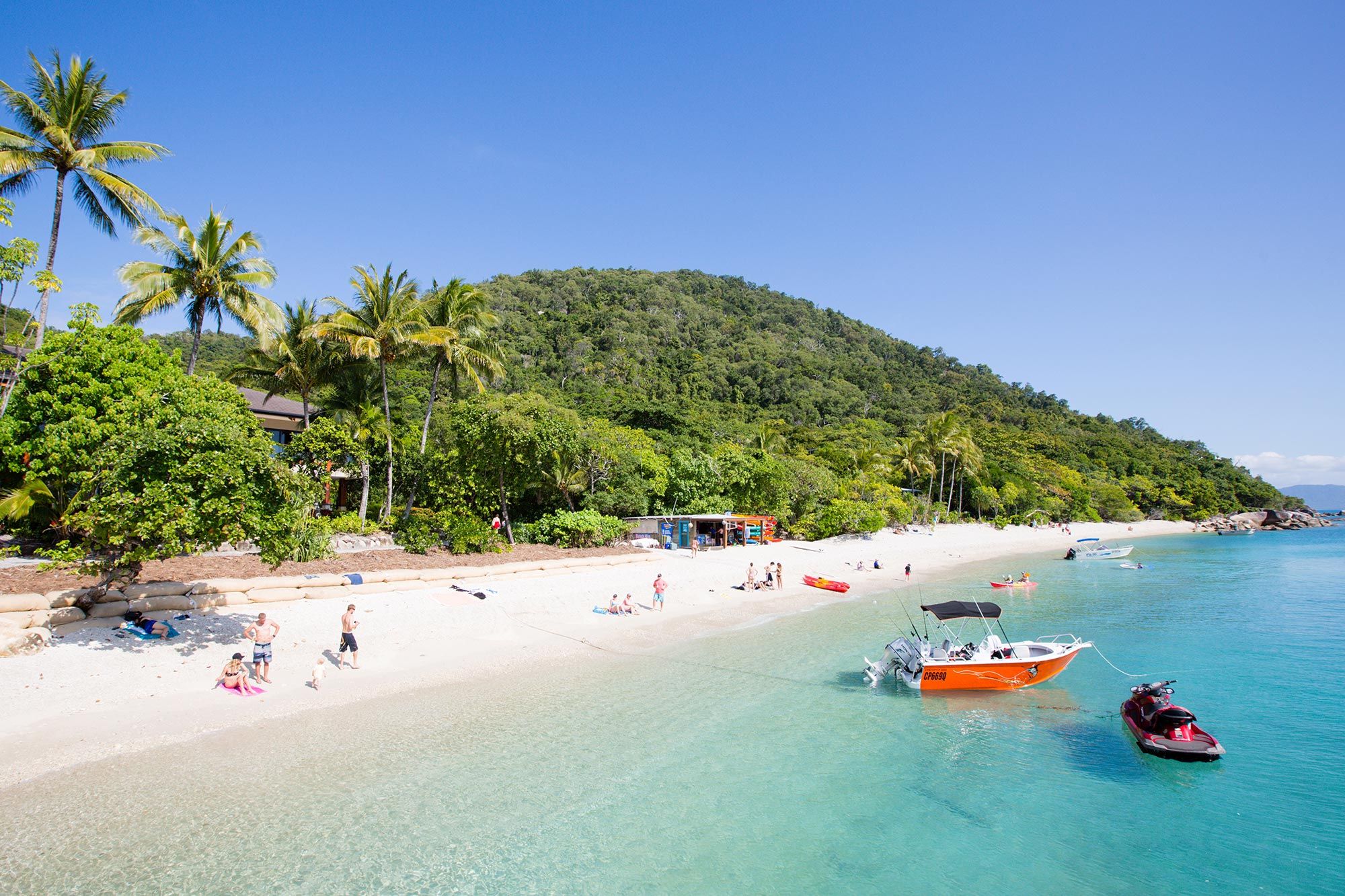 Tropical beach with boats and rainforest-covered hills